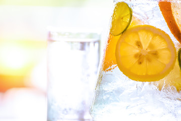 the fruit in the water and ice is on the table. the water in glass near jar.