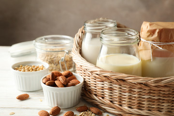 Basket with a glasses of different types milk on wooden background, space for text