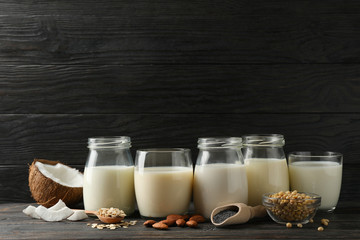 Glasses with diferent types milk on wooden background, space for text