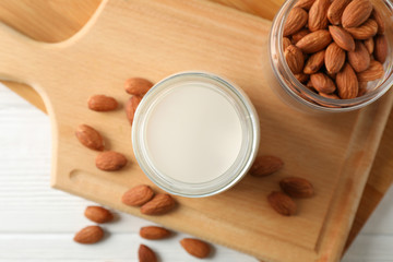 Glass of almond milk, almond seeds on white table again blue background, space for text. Top view