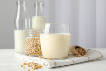 Glass of soy milk, soybeats seeds, bottle with milk on white background, space for text