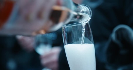 Champagne pouring into glass flute in slow motion at cocktail party
