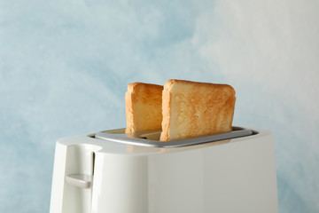 Toaster with bread slices on blue background, space for text