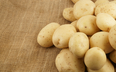 Heap of raw young potatoes on burlap background