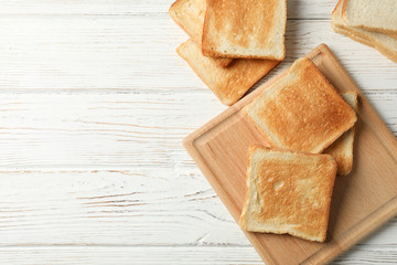 Board with toasts on white wooden background, space for text