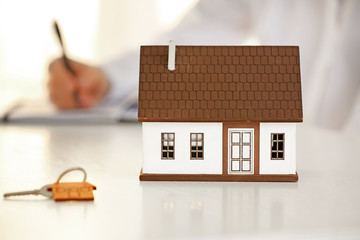 Model of house and key on table of real estate agent. Concept of buying new property