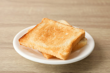 Plate with toasts on wooden background, close up