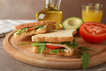 Delicious sandwiches, oil, avocado, juice and tomato on wooden board, close up