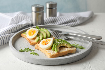 Toasts with avocado and egg, cutlery and towel on white background, closeup
