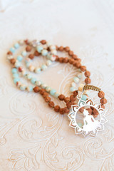 Jewelry mala necklace with natural mineral beads on white wooden decorative background
