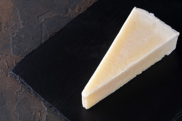 Pecorino romano, hard italian sheep milk cheese on black stone board, selective focus