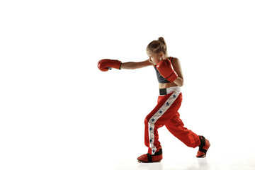 Young female kickboxing fighter training isolated on white background. Caucasian blonde girl in red sportswear practicing in martial arts. Concept of sport, healthy lifestyle, motion, action, youth.