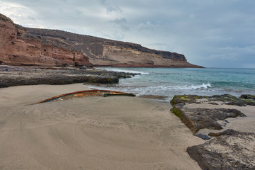 small sunken ship on the shore of a beach in Caleta de Adeje, Tenerife