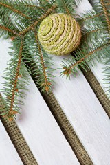 Fototapeta na wymiar Fir branch and decorative balls on a background of wooden boards. The boards are painted white.