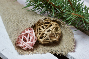 Fir branch and decorative rattan balls in linen fabric on a background of wooden boards. The boards are painted white.