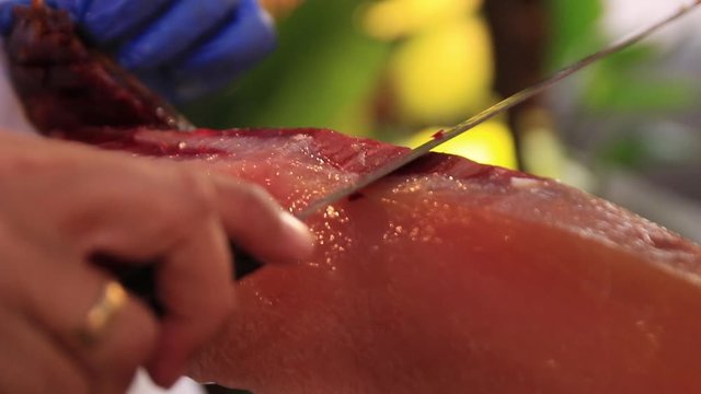close up shot of an expert finely slicing some spanish serrano iberico jamon ham. A delicacy to the Andalucian region, the animals are fed acorns which supplements the juicy oily meat.