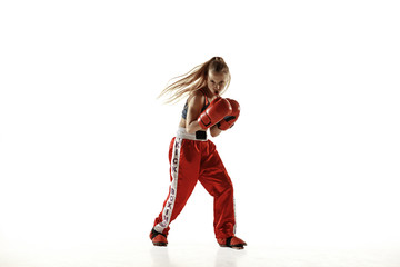 Fototapeta na wymiar Young female kickboxing fighter training isolated on white background. Caucasian blonde girl in red sportswear practicing in martial arts. Concept of sport, healthy lifestyle, motion, action, youth.