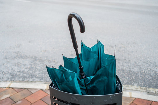  image of a broken and abandoned umbrella in a trash bin on a street
