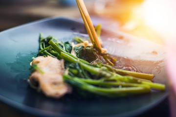 the food is on the dish and vegetable and chopsticks.