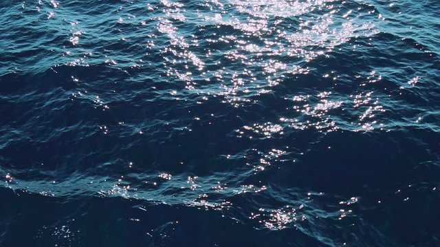 Slow Mo of sunlit blue sea waves on water surface. Real water ripple. Close up liquid textured surface background