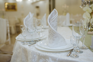 Restaurant decorated with white elements, and tables with crystal dishes.