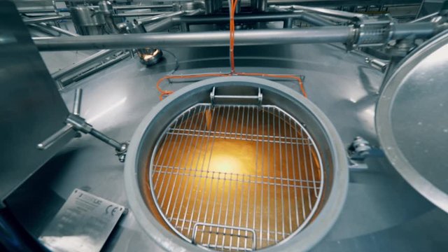 Cheese production process. Metal cistern with dairy substance getting cooked in it