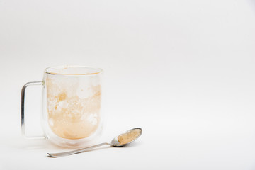 A cup of hot latte coffee that is completely drained with coffee Spoon on a white background.