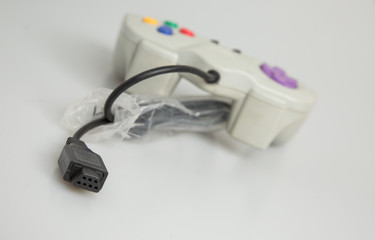 Fototapeta premium Retro vintage games console controller purple black white red blue green yellow isolated dirty used video game marked scuff wire cable kids playing adults nostalgia old technology shop studio lighting