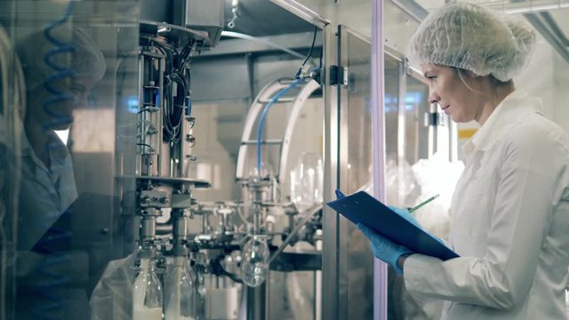 Female worker is taking notes at the dairy factory