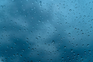 Fresh water drops after raining on blue glass window background in car.