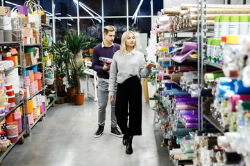 Cute couple guy and girl choose paper for gift wrapping for winter holidays. . Time for gifts