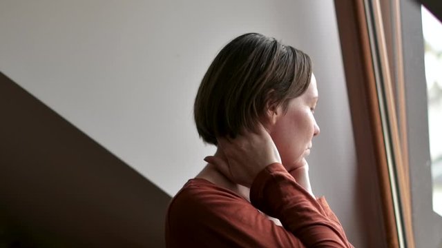 Woman with severe neck pain in loft apartment, selective focus
