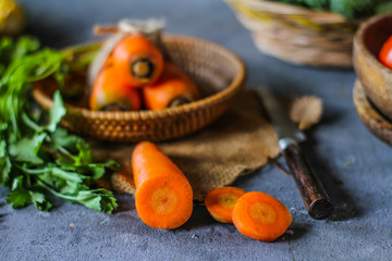 Photo of Fresh Carrots On A Plate. On wooden dark background. Bunch of fresh carrots with green leaves on Wooden Cutting Board. Carrot around vegetables, salt, black pepper, corn, broccoli. Image
