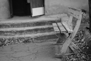Old wooden bench with peeling paint in old city yard, bw photo.