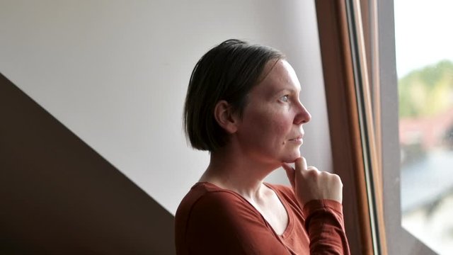 Sad woman looking out of the window in loft apartment