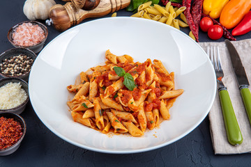 Penne pasta with chili sauce arrabiata. Classic italian penne arrabiata with basil and freshly grated pecorino cheese on a rustic wooden table. - obrazy, fototapety, plakaty