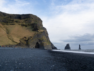 Overview of the famous Reynisfjara Black Sand Beach, with the H&aacute;lsanefshellir Cave and the Reynisdrangar, the enormous basalt sea stacks. South Coast of Iceland.