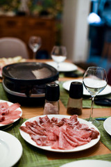 Raclette table setting with cheese and delicatessen 