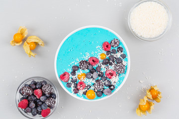 Breakfast smoothie bowl with blue spirulina, yogurt, raspberries, blueberries, Blackberries, physalis and coconut flakes. Detox smoothie bowl. Vegan food.