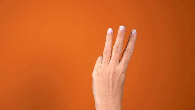 Closeup of isolated female hand counting backward from 5 to 0. Woman shows five first, then four, three, two, one  fingers. Manicured nails painted with french style pink polish. Math concept. 4k 