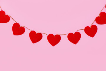 Hearts garland hanging on pink background.