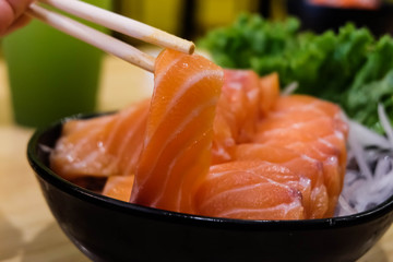 Sasimi Chopsticks, salmon, on a black cup, close up, green background