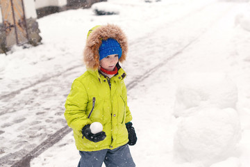 Kid playing on snow in winter holiday. Cute little boy in warm clothes outdoors in winter