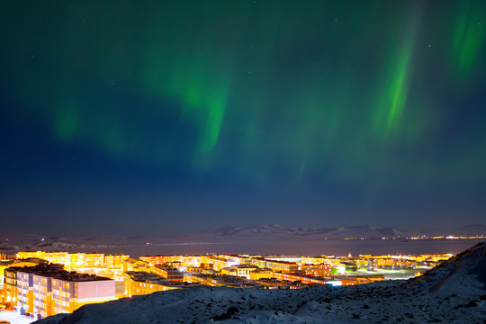 Majestic arctic landscape with aurora borealis over the northern city of Anadyr. Panorama of the city and the northern lights in the sky. Location place: Anadyr, Chukotka, Siberia, Far East of Russia