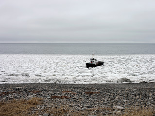 Obraz premium Sea tug goes to shore through broken ice.