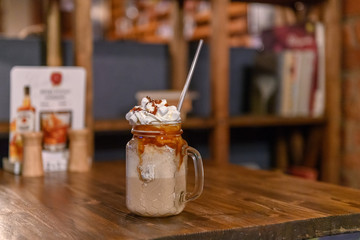 Glass mason jar with ice latte coffee  on wooden table in a coffee shop