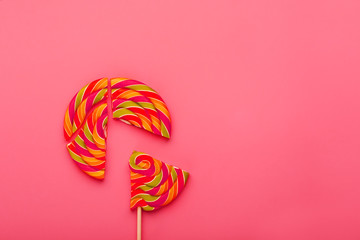 Lollipop broken into pieces on pink background, top view with copy space.