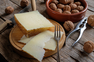 Manchego cheese and nuts on rustic wooden table