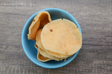 A bowl of prawn crackers on wooden background