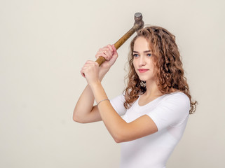 Pretty girl holds a hammer in hands, swings to strike